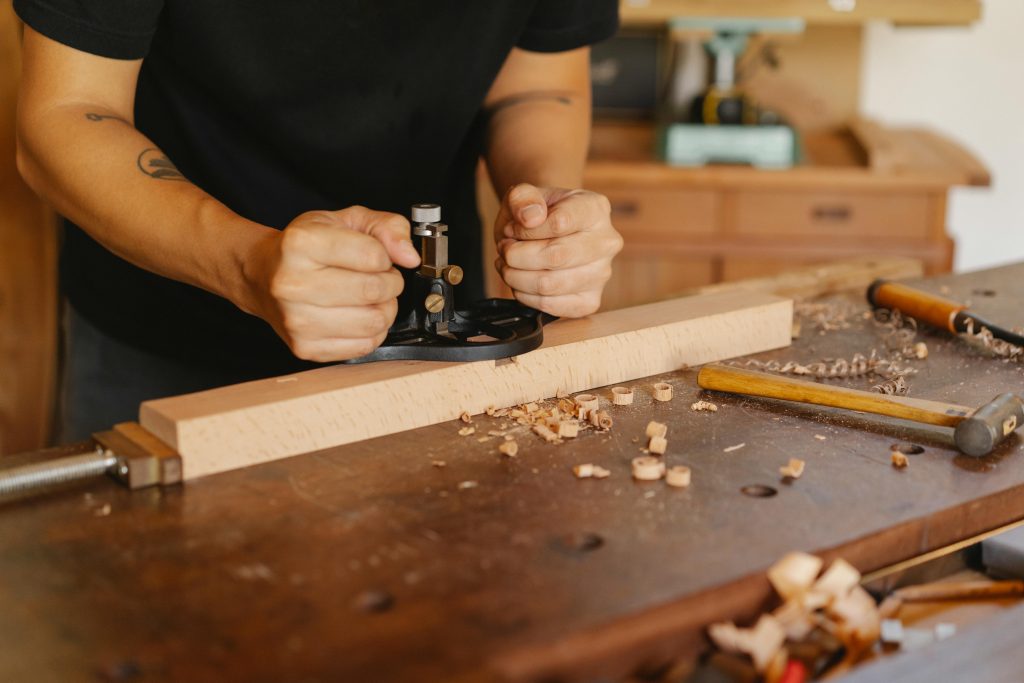 A skilled woodworker carefully crafting a wooden piece with hand tools in a workshop setting.